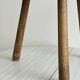 Small antique tripod stool in light wood, half-moon seat.