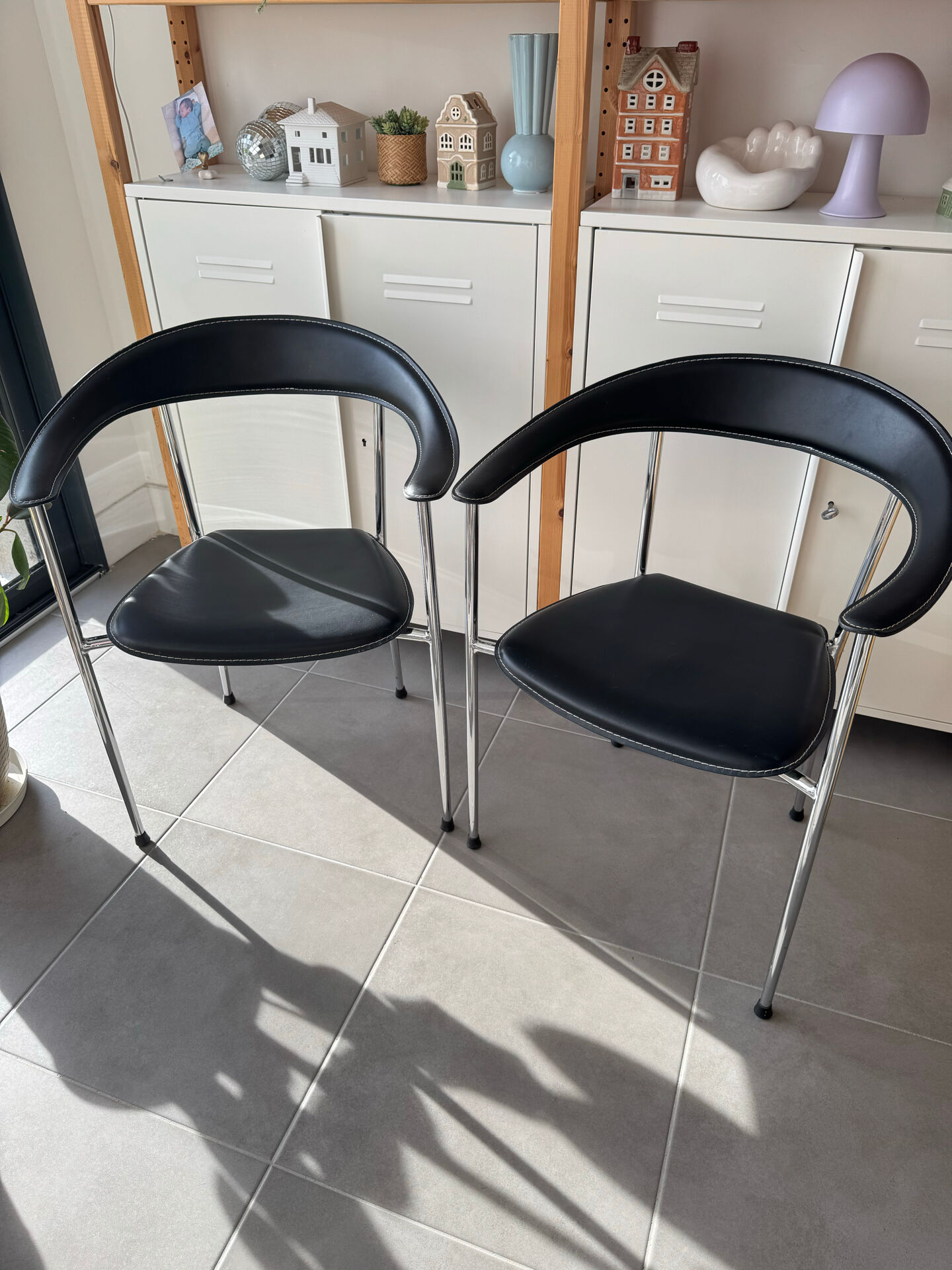 Set of two metal chairs with a brushed finish and black leather.