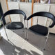 Set of two metal chairs with a brushed finish and black leather.