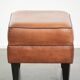 Handy sheepskin ottoman with warm colours finished with black piping