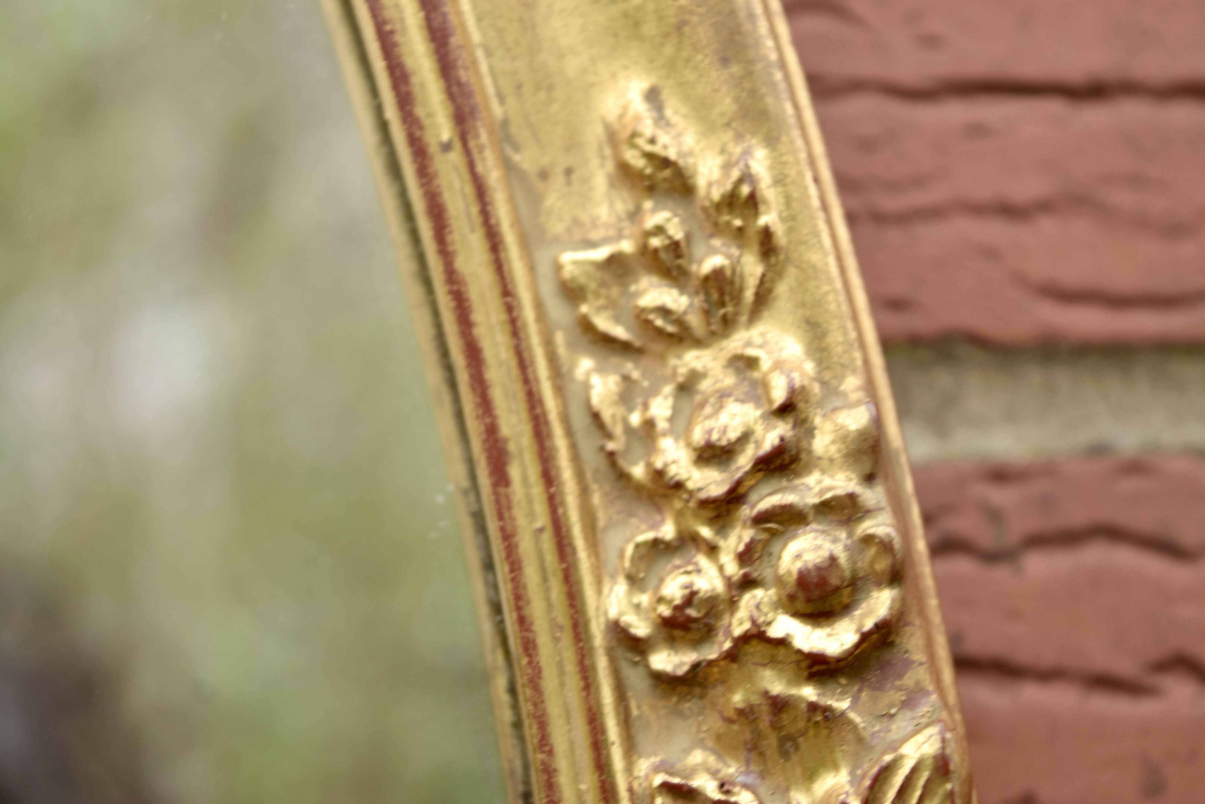 Old large oval wall mirror in golden resin