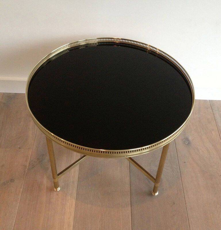 Round coffee table in brass with a black lacquered glass top by Maison Jansen.