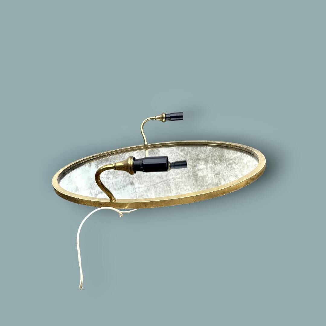 Oval wall mirror in gilded brass with double sconces – 1950s/60s
