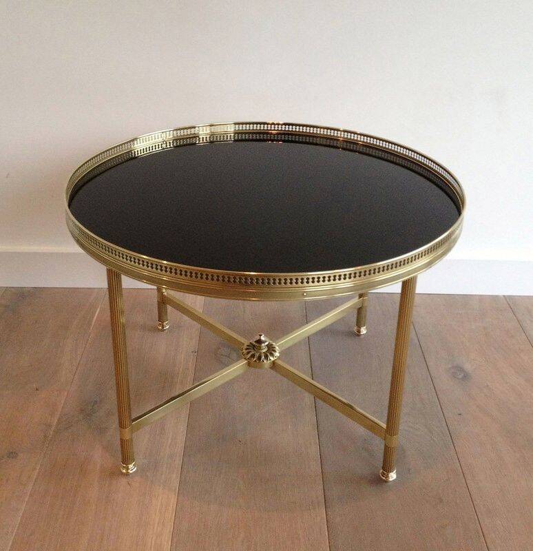 Round coffee table in brass with a black lacquered glass top by Maison Jansen.