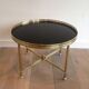 Round coffee table in brass with a black lacquered glass top by Maison Jansen.