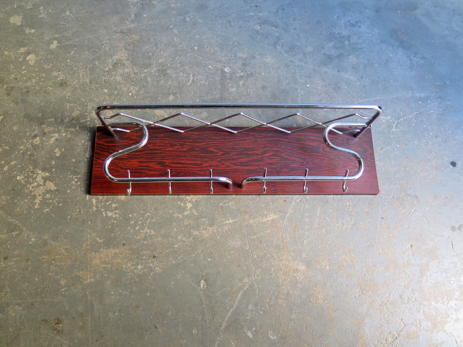 Chrome metal patere in a wooden support panel coat veneer.