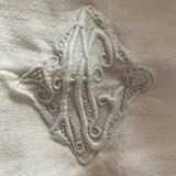 Damask tablecloth with a floral pattern and a central embroidered monogram.