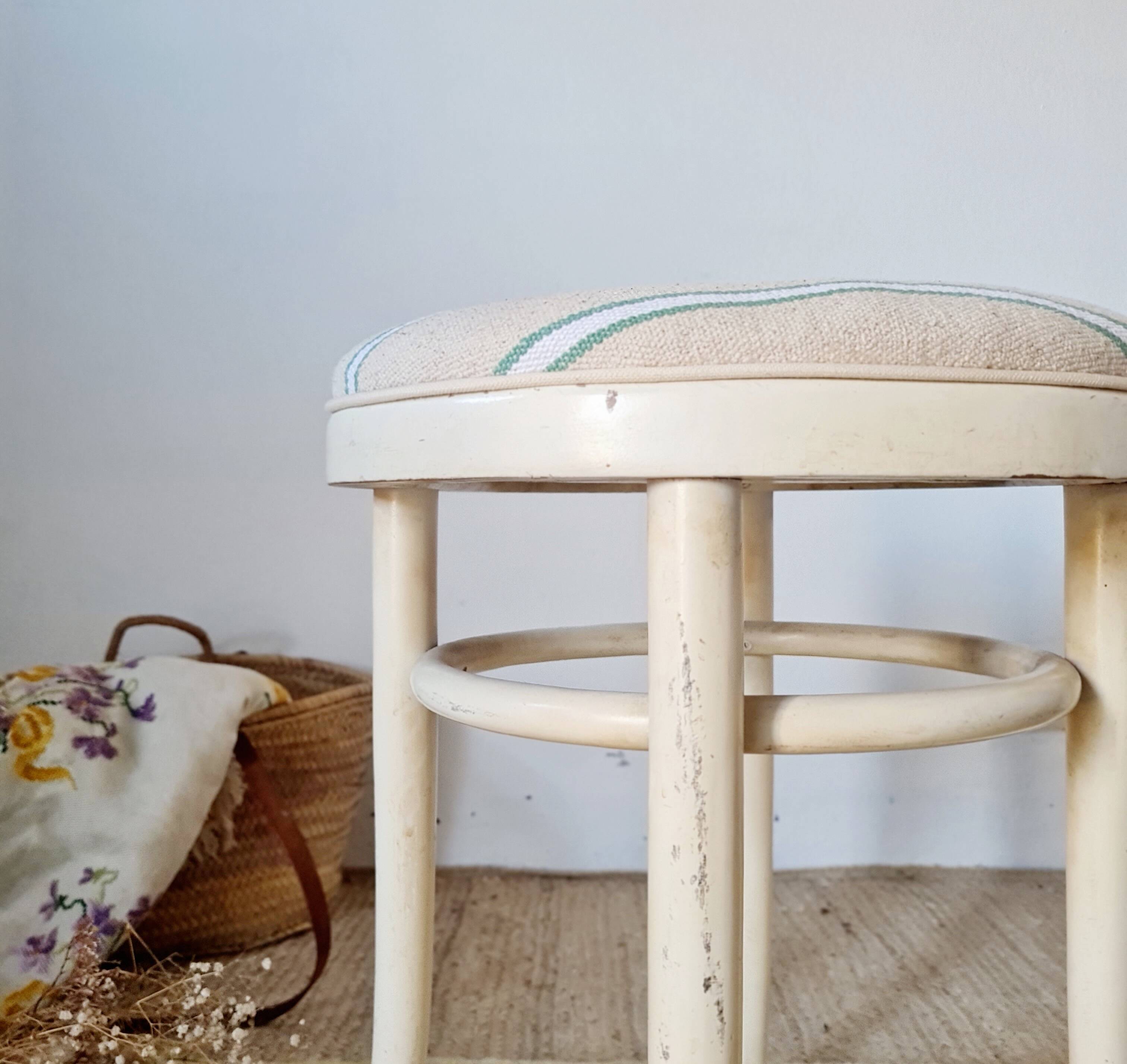 Antique stool with a wooden frame and a cream and green striped fabric seat.