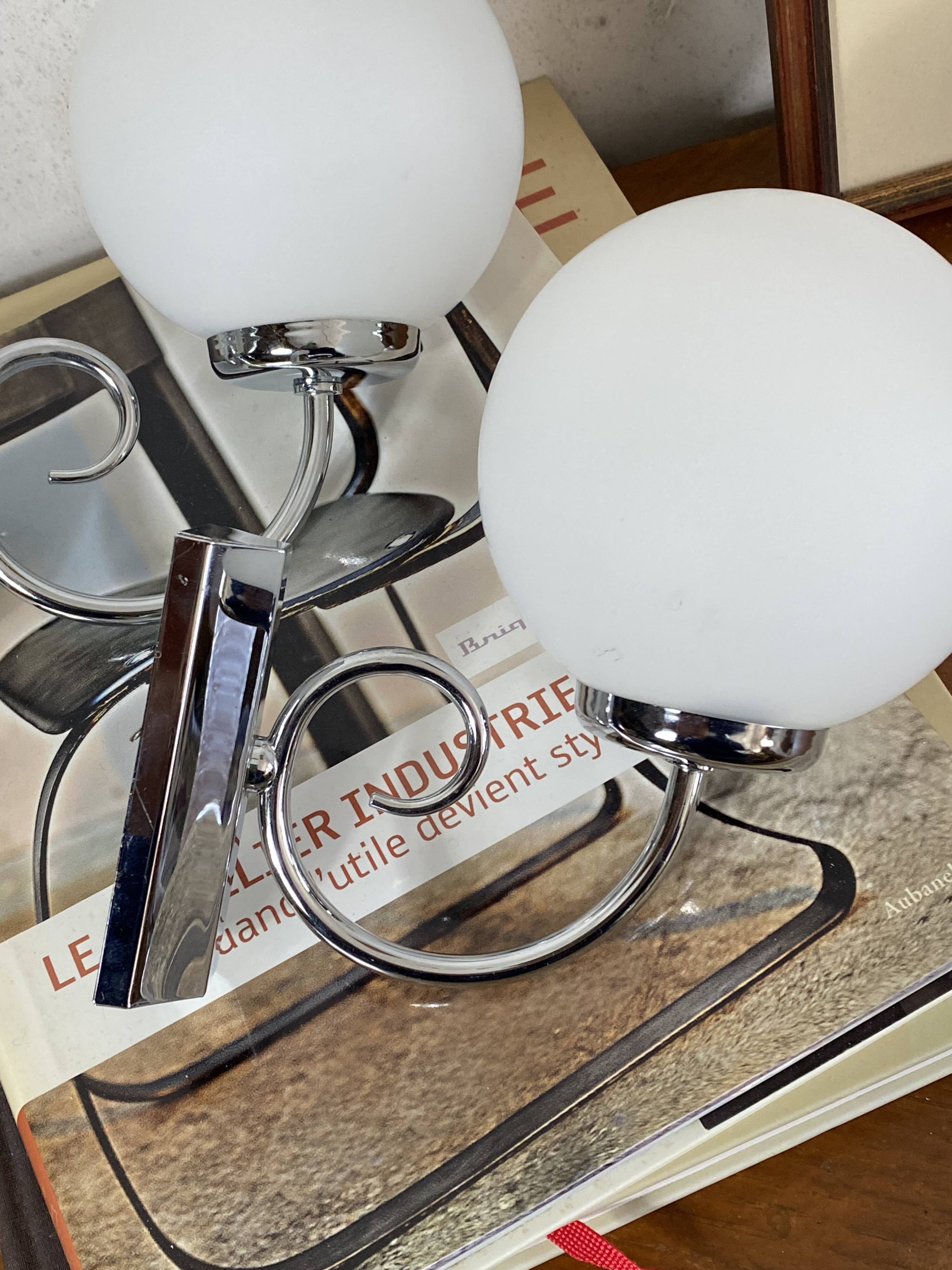 Pair of wall sconces in stainless steel with white glass globe.
