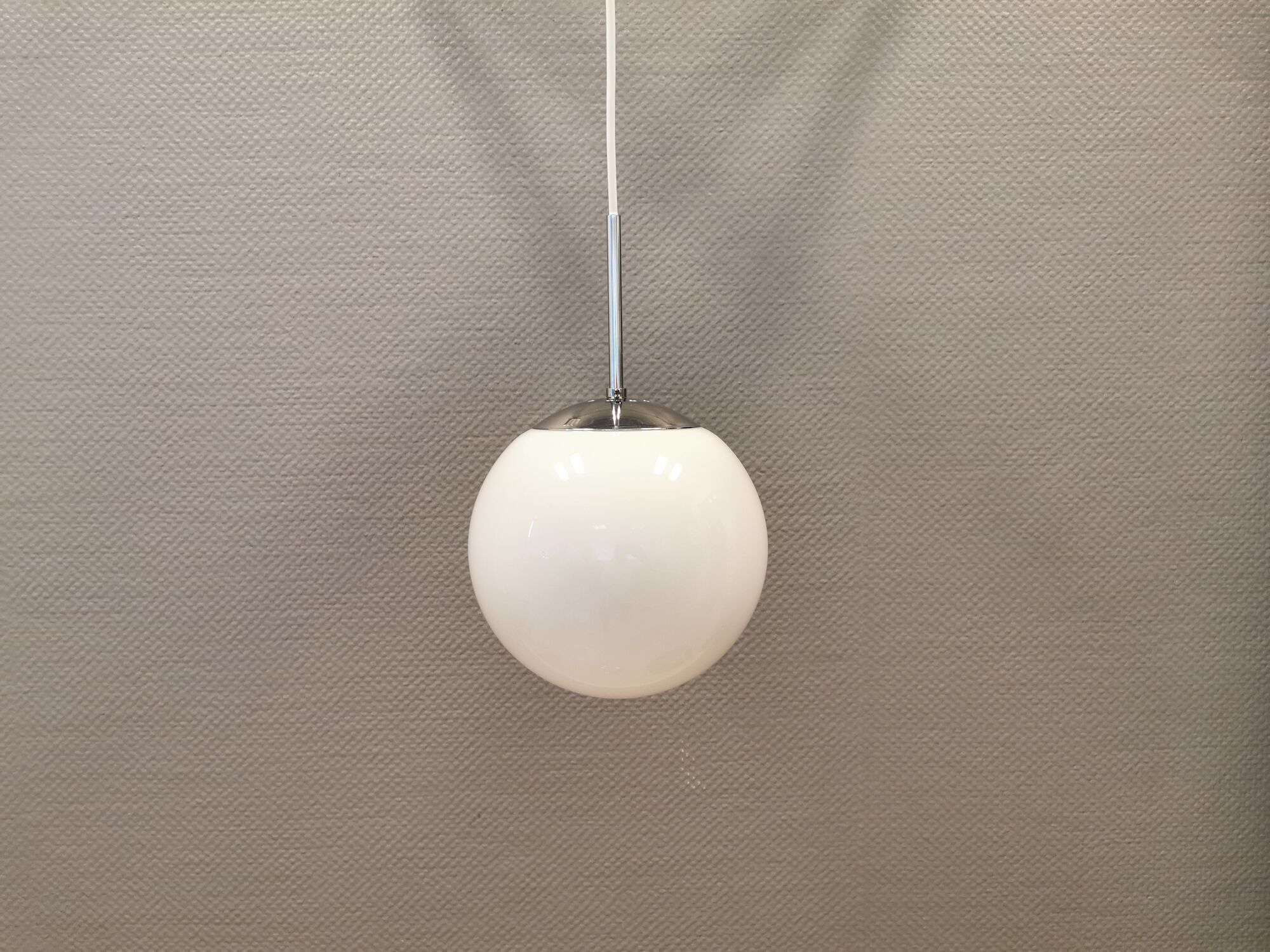 White hanging lamp with metal suspension, made with ball round opal glass shade.