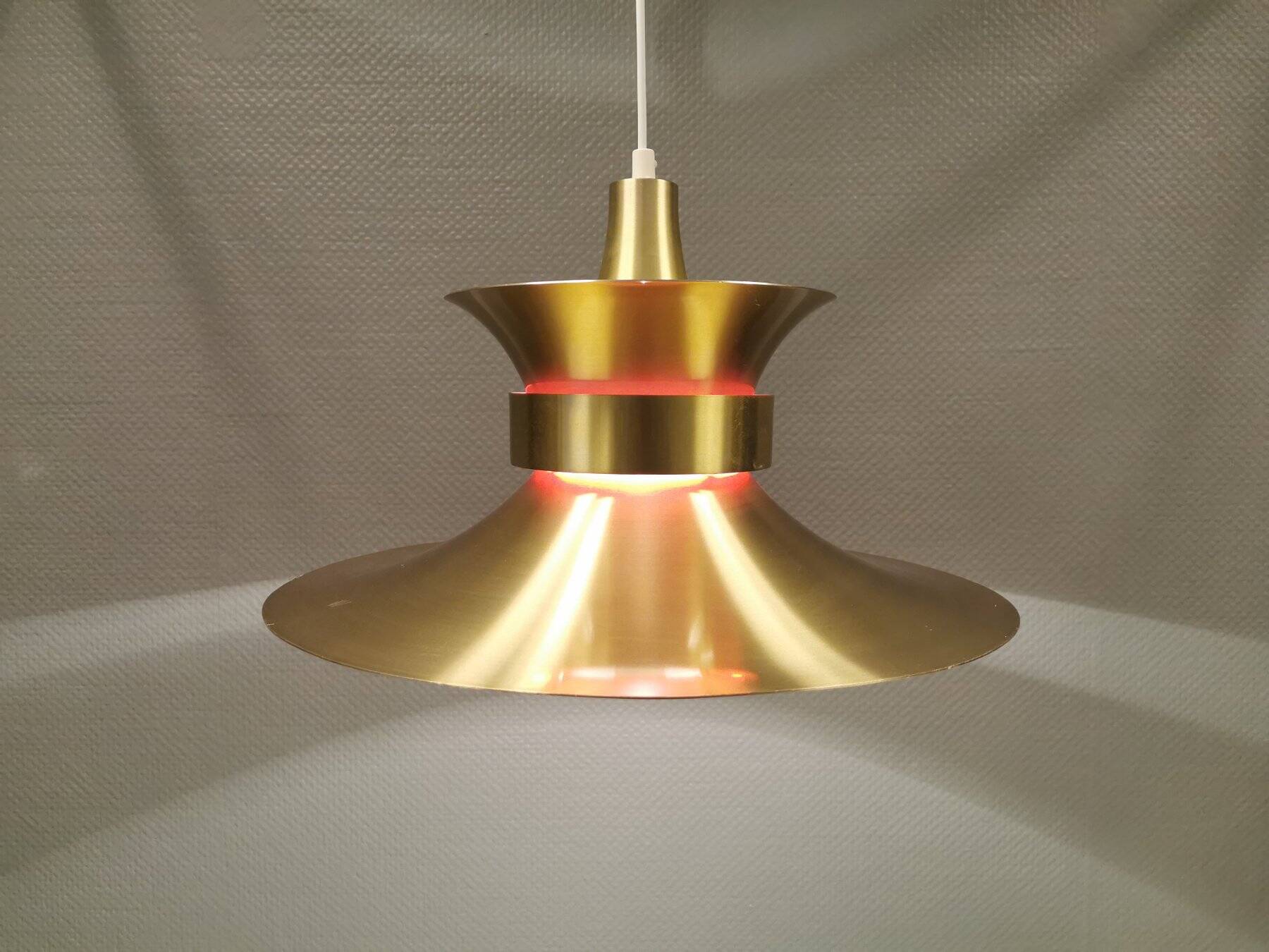 Large hanging lamp, made of brass-coloured aluminium with red and white contrast lacquer inside.