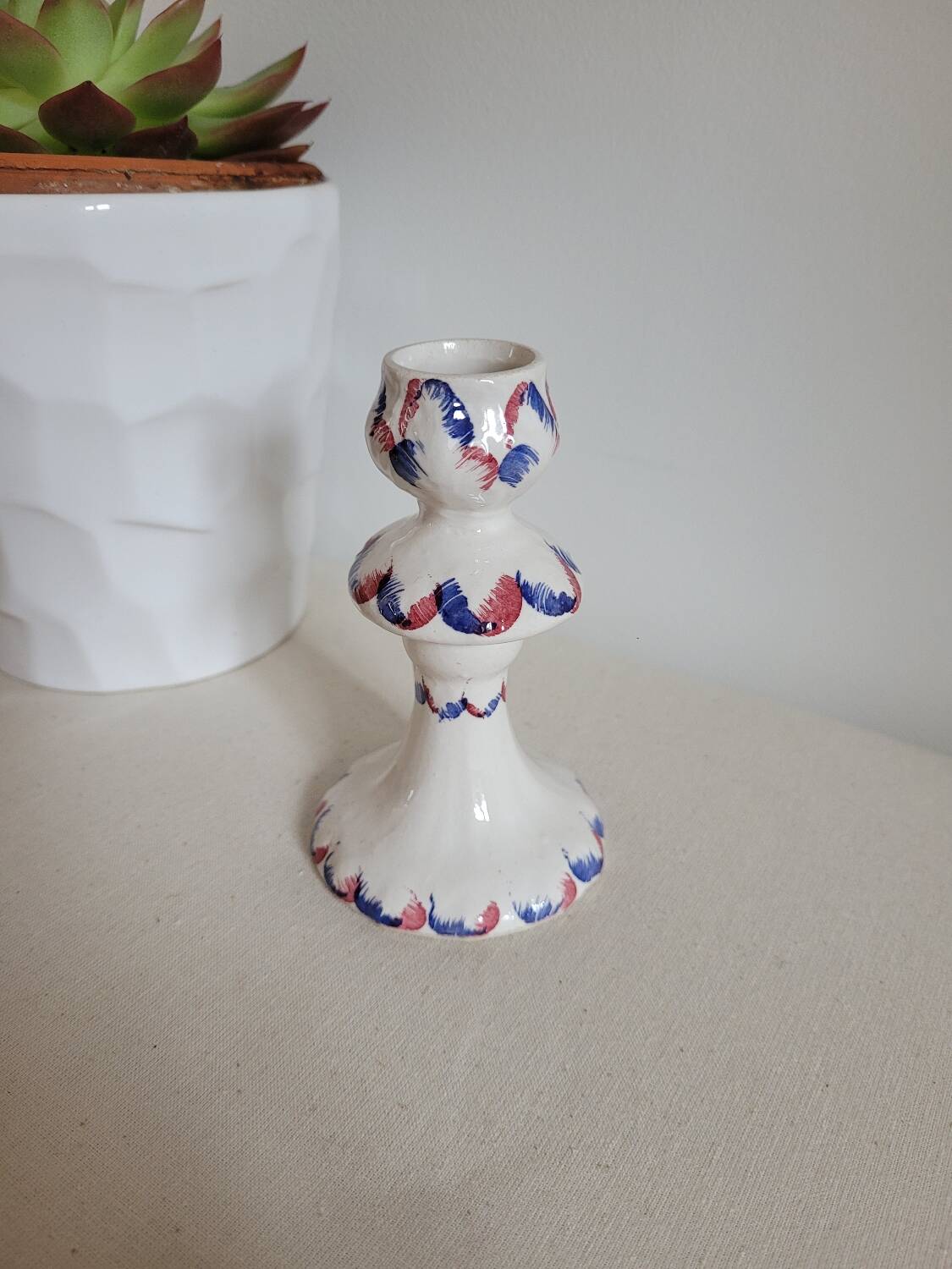 Ceramic candlestick with red and blue decoration.