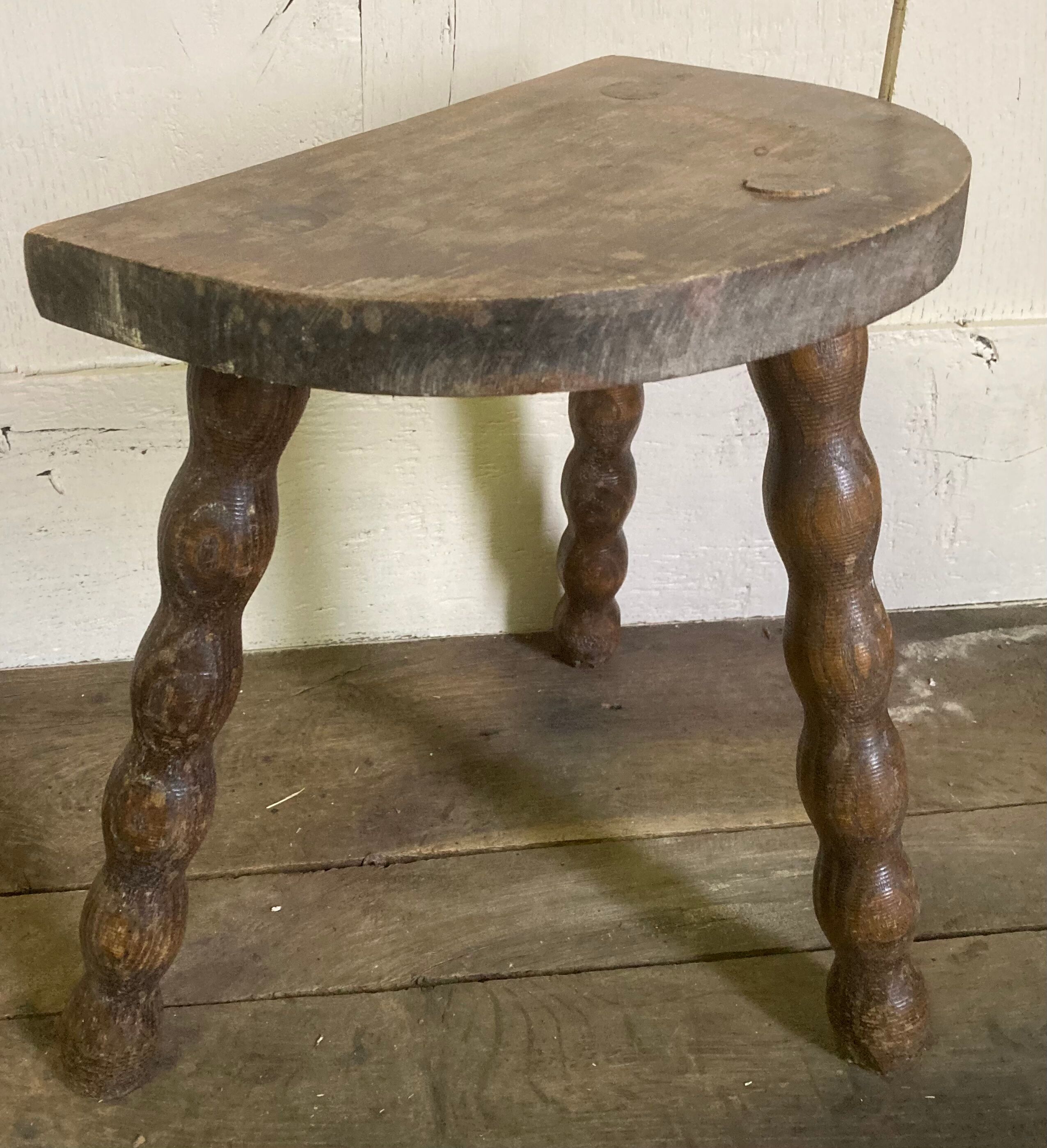 Half-moon tripod stool.