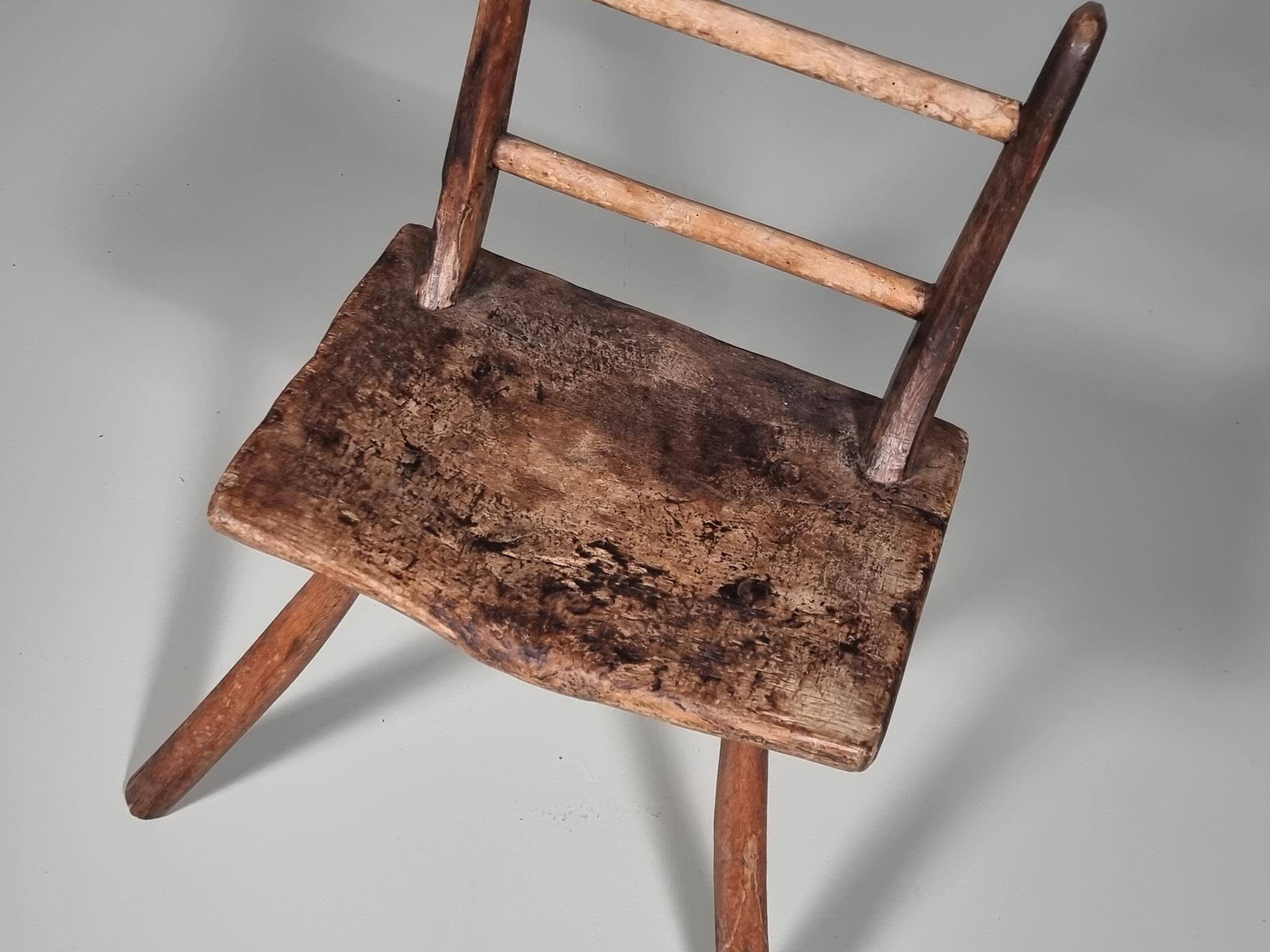 Rustic Wabi-Sabi style accent chair in dark curved hardwood, 1900s.