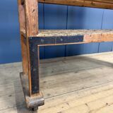Old wooden workshop shelf with cast iron wheels.