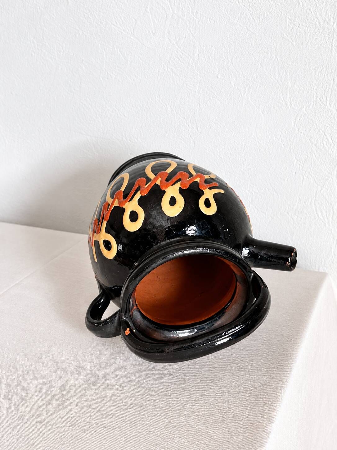 Old vase in glossy black ceramic, vintage exterior decoration.