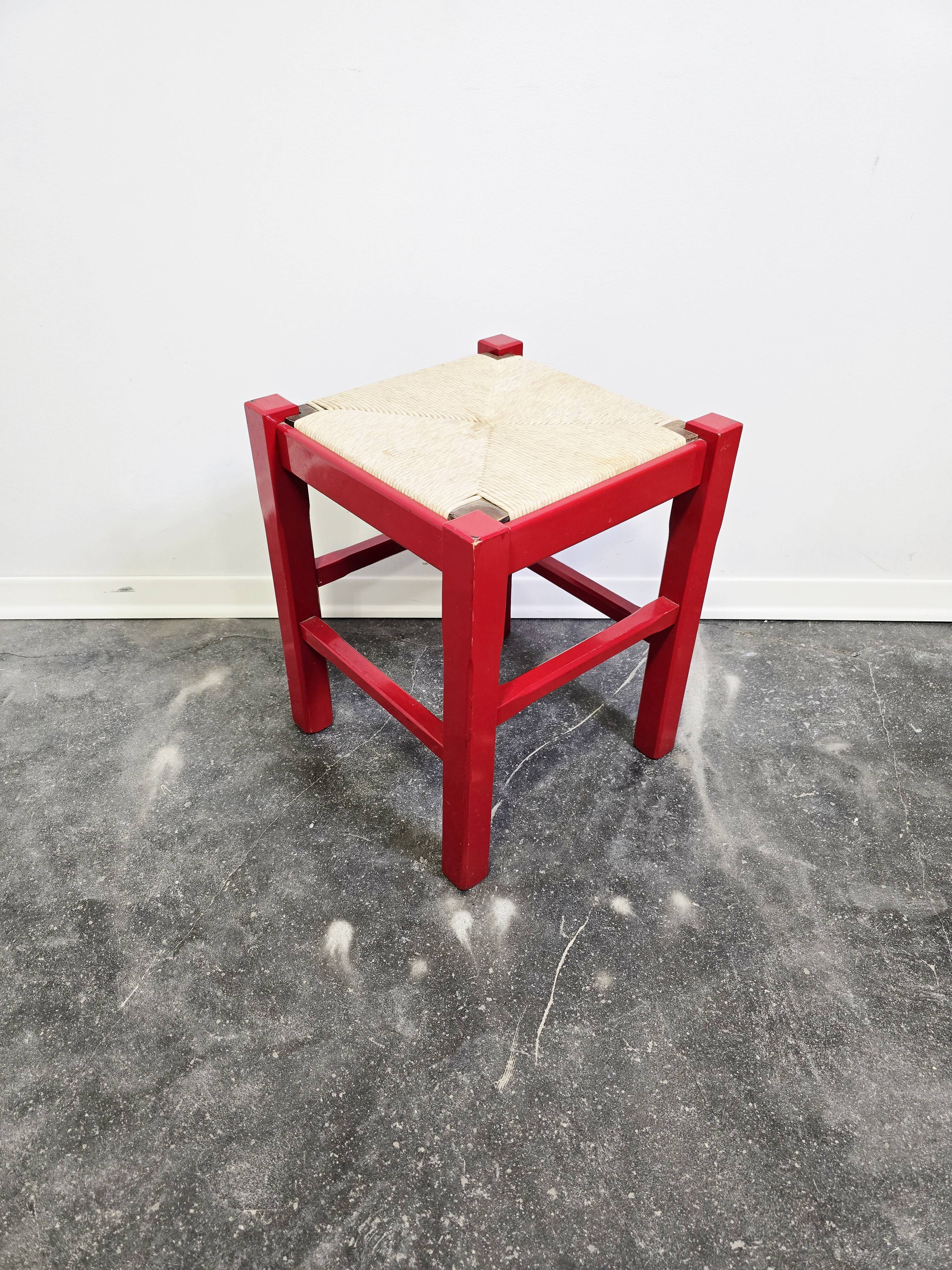 Red wooden stool with woven rush seat.