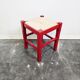Tabouret en bois rouge avec assise en paille tressée.