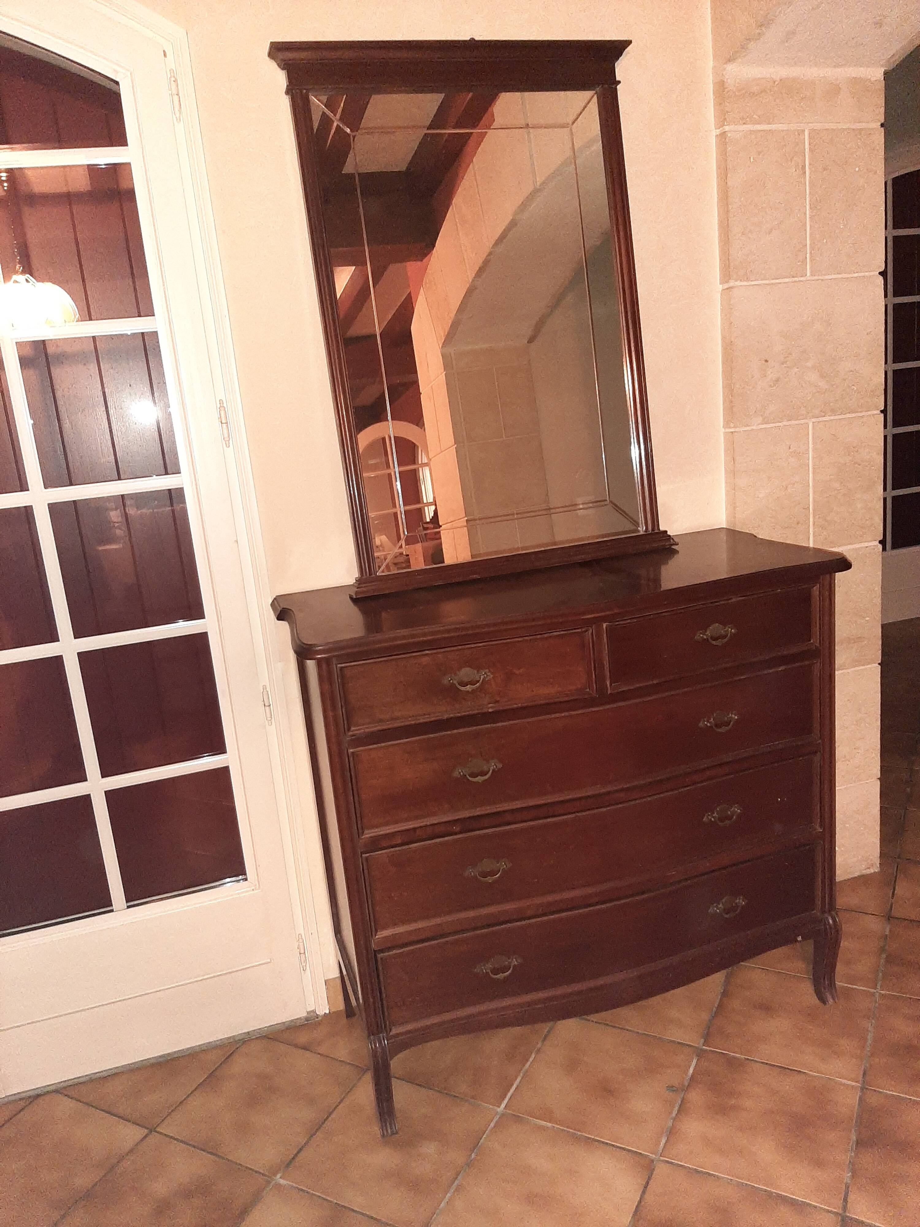 Style set: bevelled mirror and curved wooden chest of drawers.