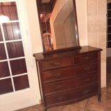 Style set: bevelled mirror and curved wooden chest of drawers.