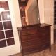 Style set: bevelled mirror and curved wooden chest of drawers.