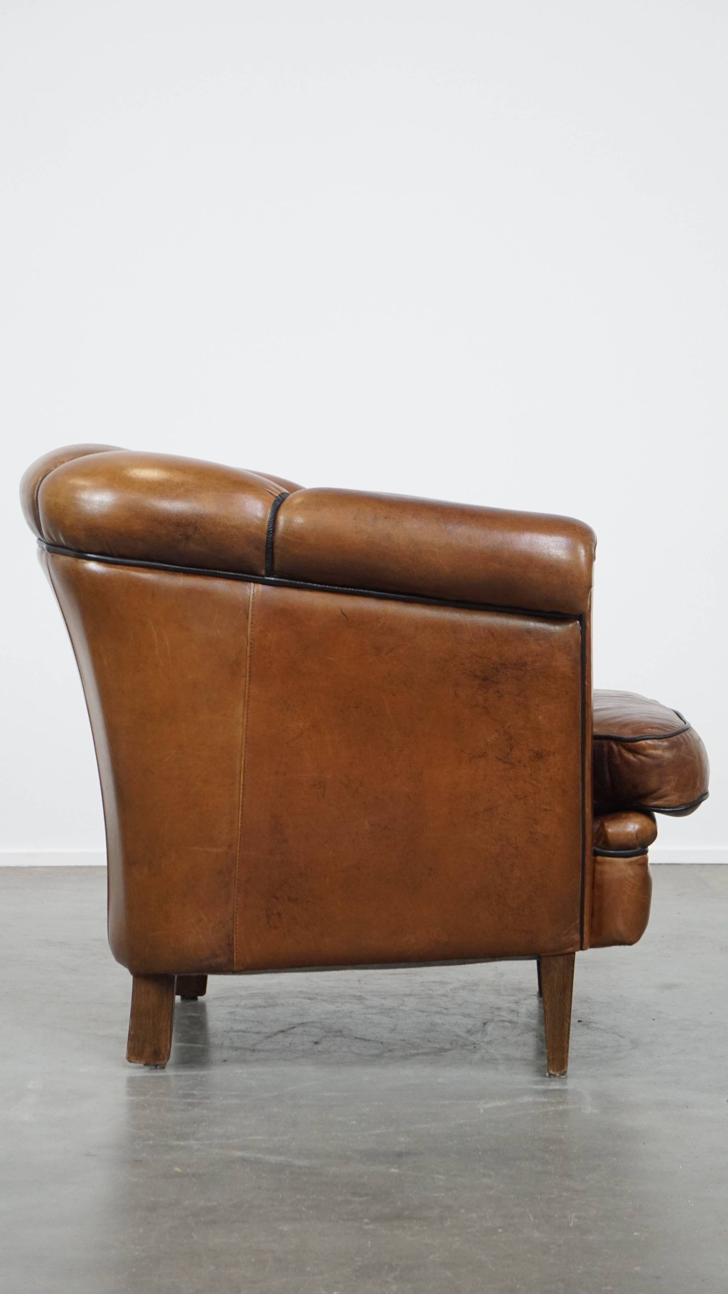 Unique vintage cognac-coloured leather club armchair with black piping