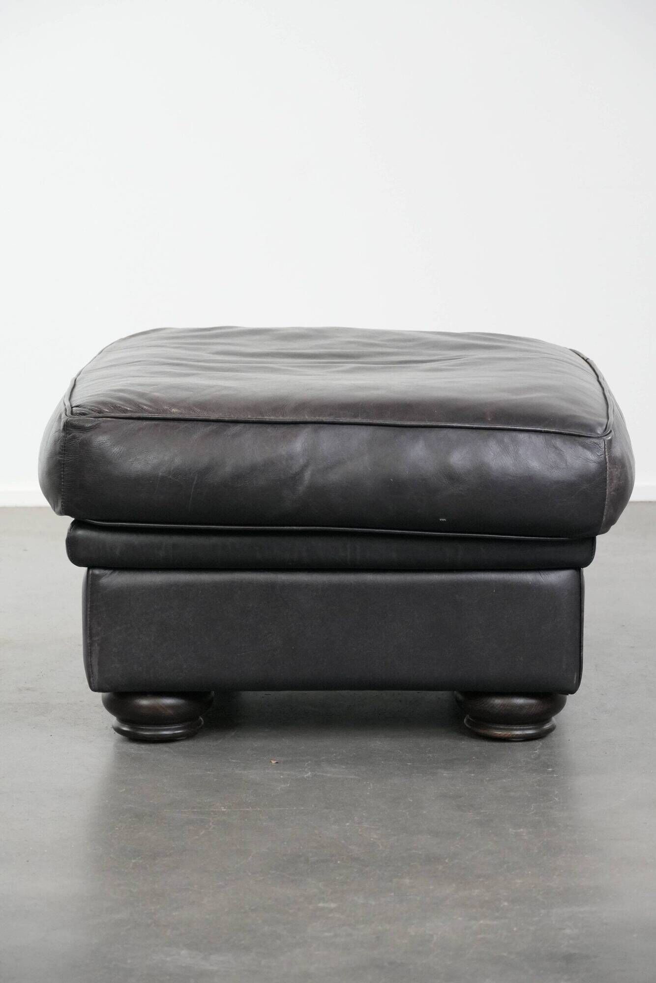Set of a black cowhide leather Chesterfield armchair and matching ottoman