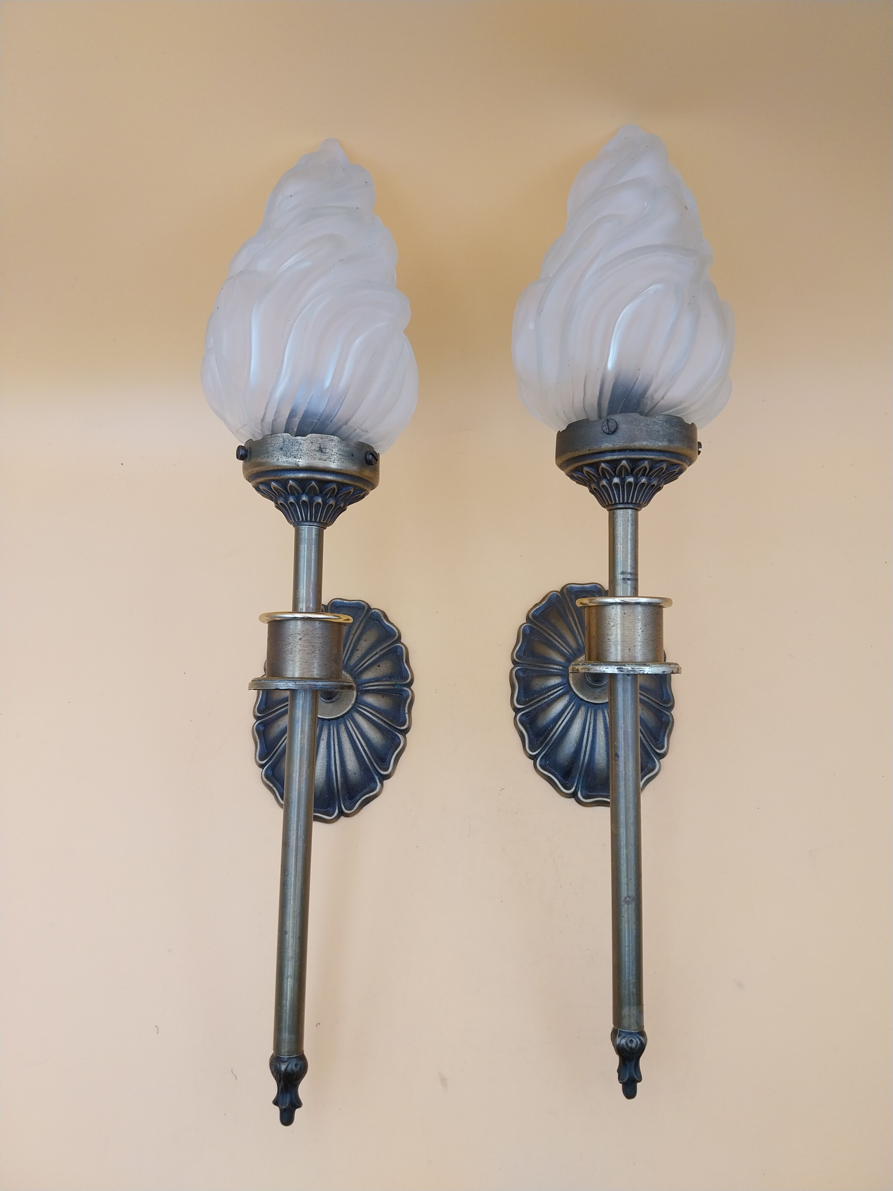 Pair of brass torch wall lights with globe flame.