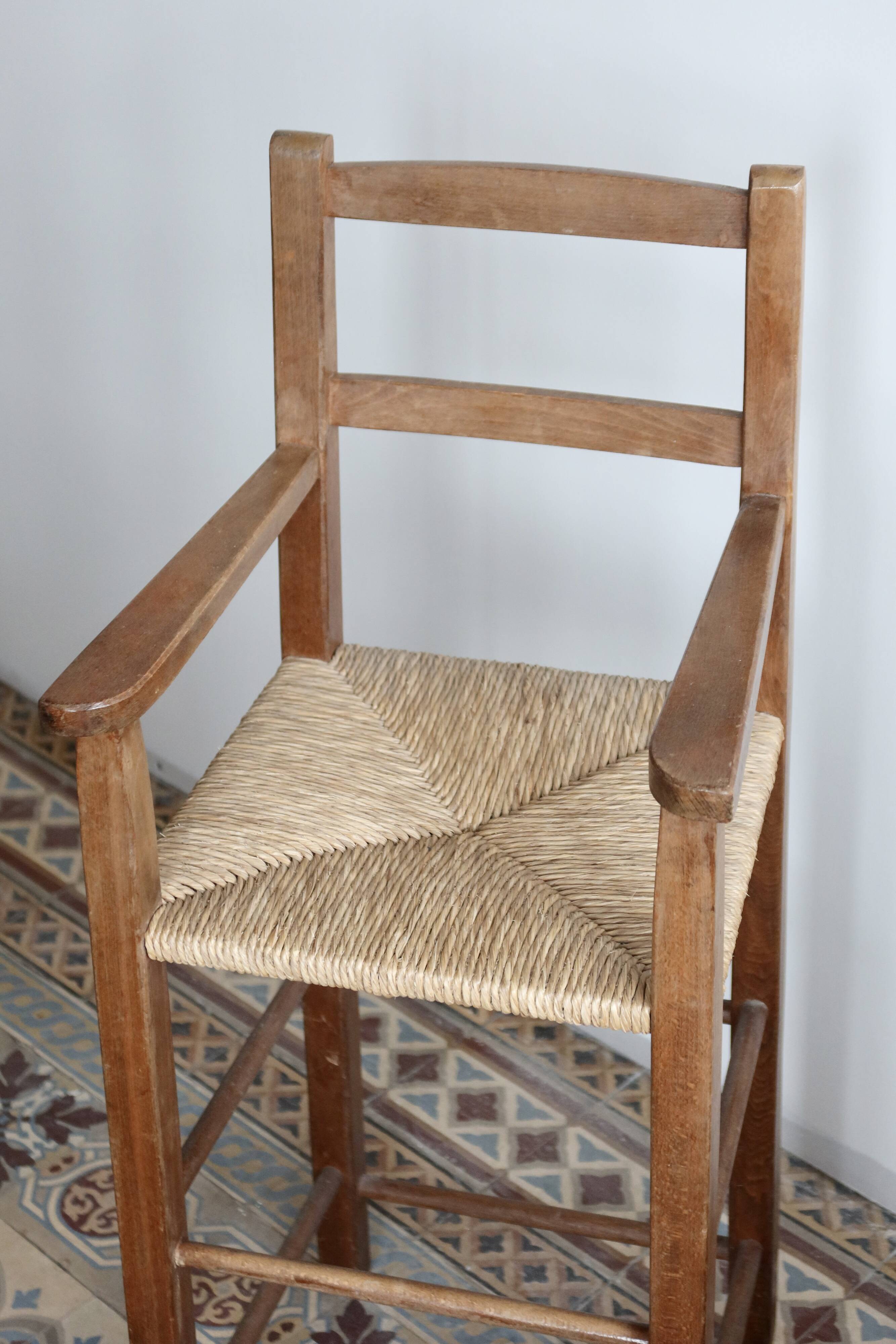 Vintage wooden high chair for children with a straw seat.