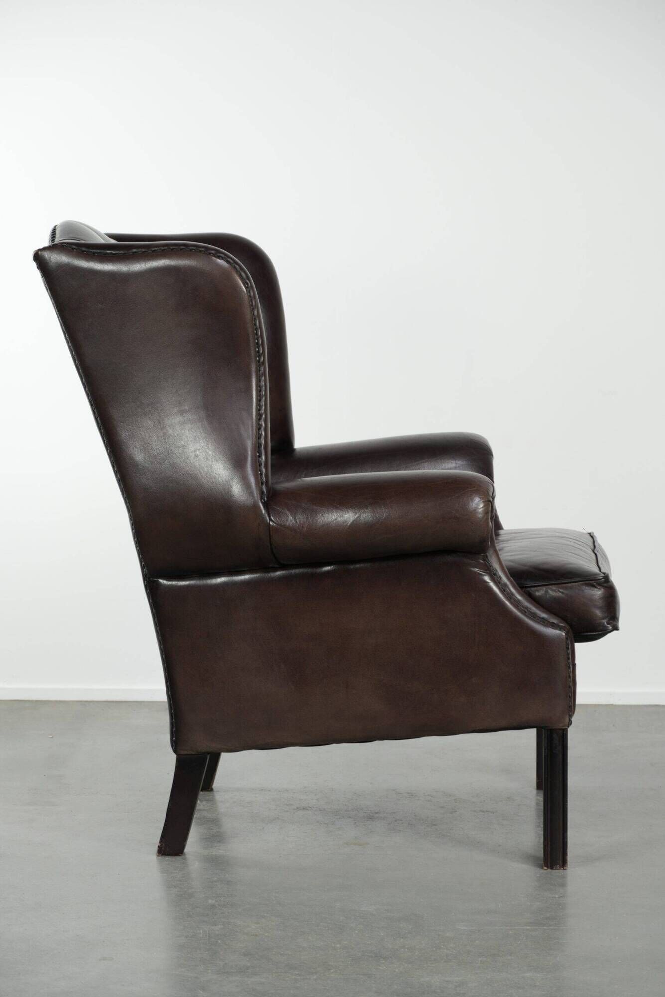 Dark brown cowhide Chesterfield wingback armchair in classic English style