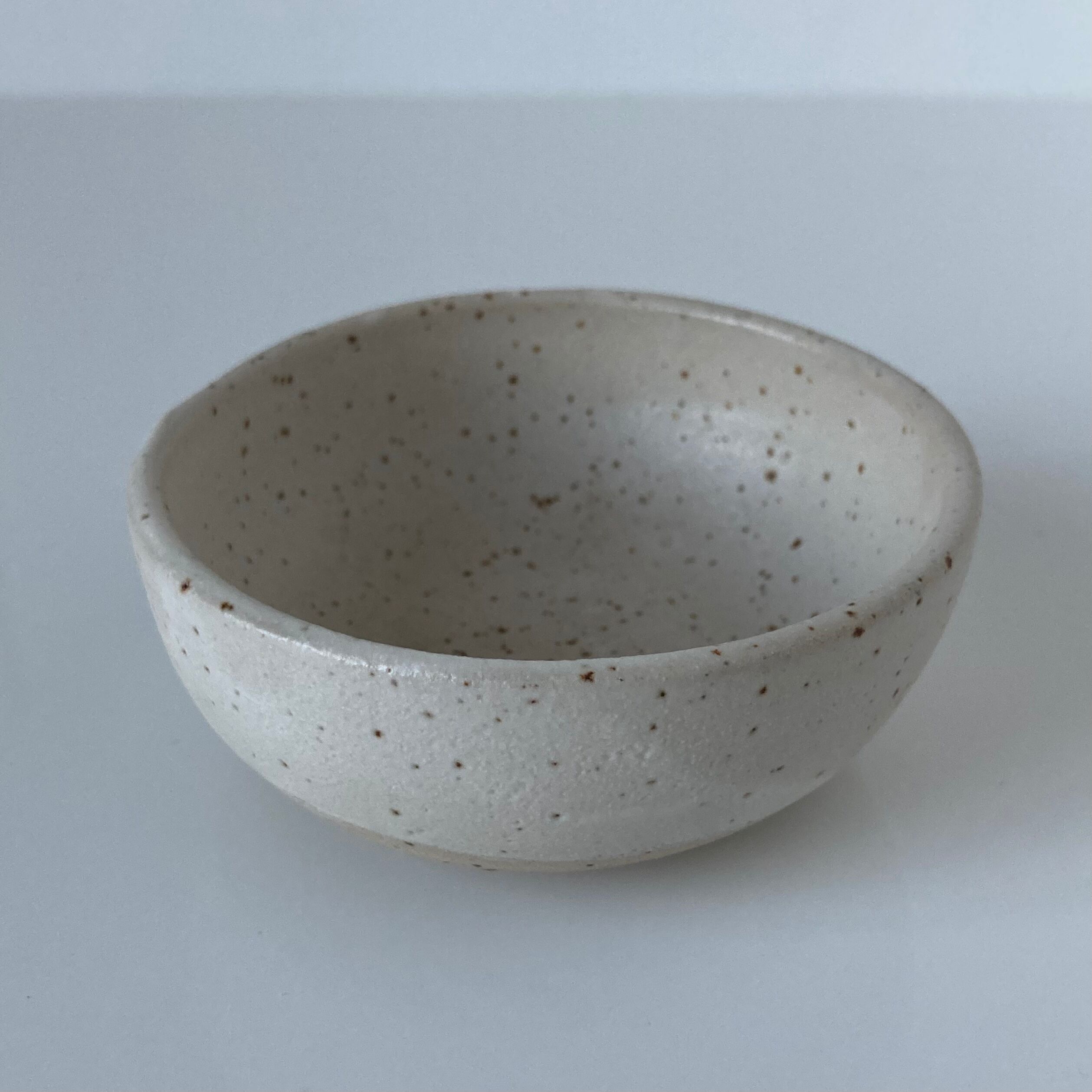 Meeting of three artist's ceramic objects including two pots and a cream covered bowl