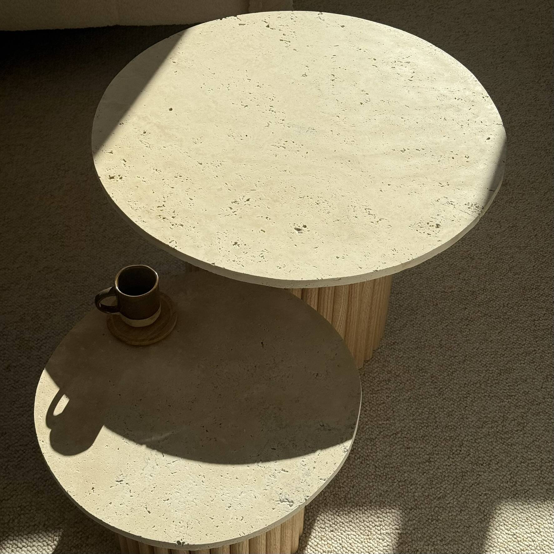 Round nesting coffee table in travertine and raw fluted wood.