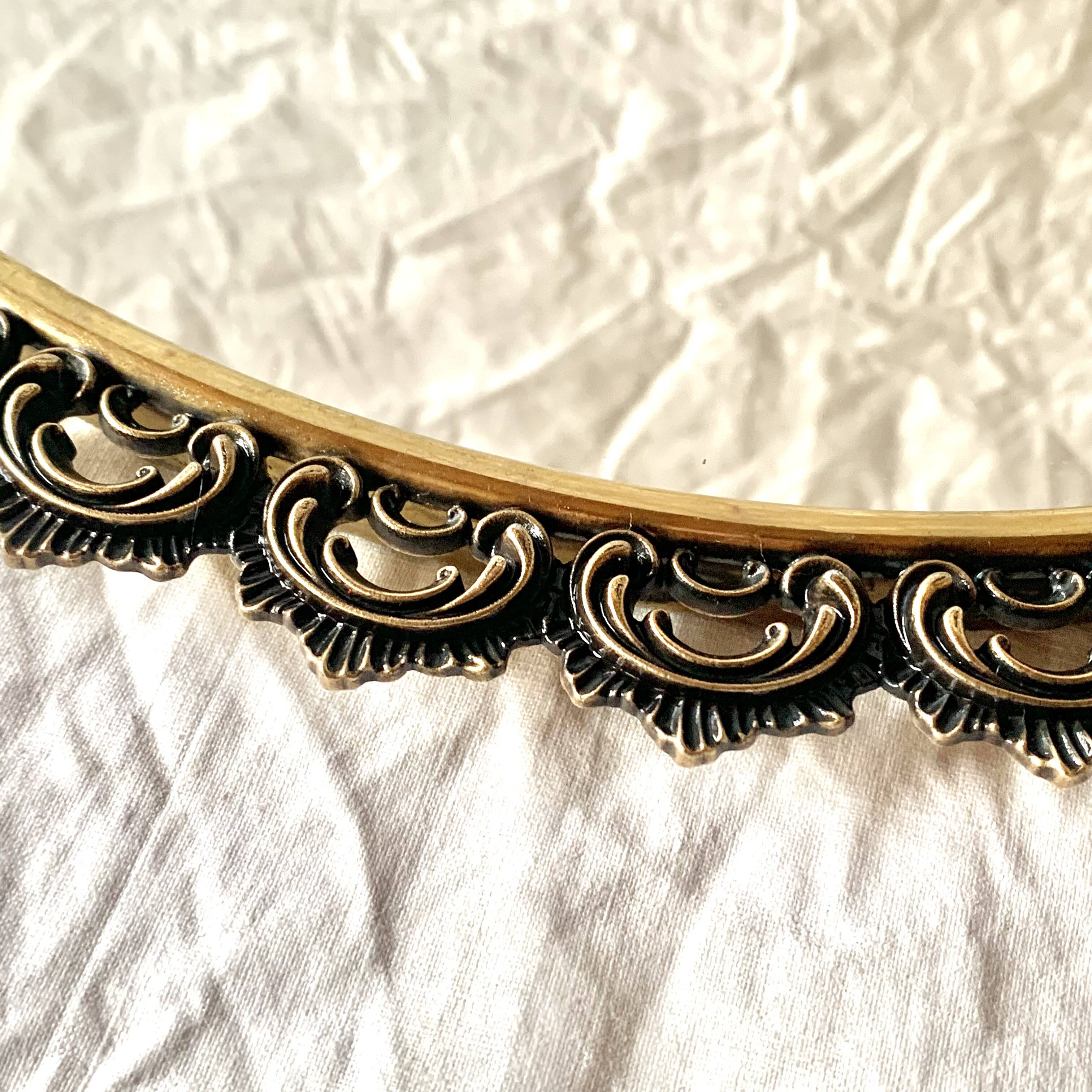 Old oval wall mirror in gilded brass