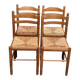 4 solid wood kitchen chairs with straw seats in a country farmhouse style.