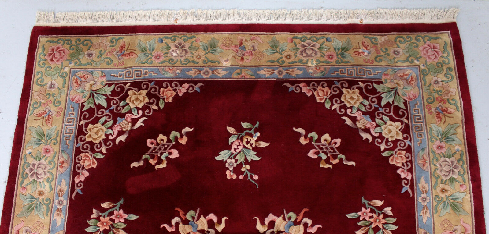 China wool fringed rug with floral pattern on deep plum background 393x274cm