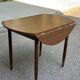 Round kitchen table with extendable leaves in dark wood.