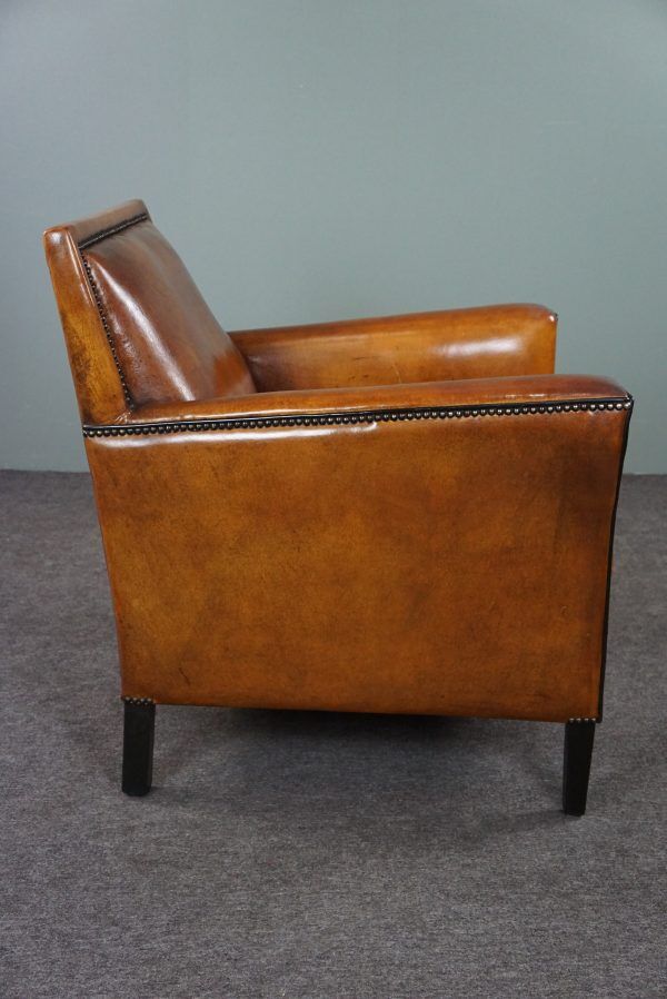 Art deco armchair in sheepskin with black piping and decorative nails
