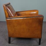 Art deco armchair in sheepskin with black piping and decorative nails