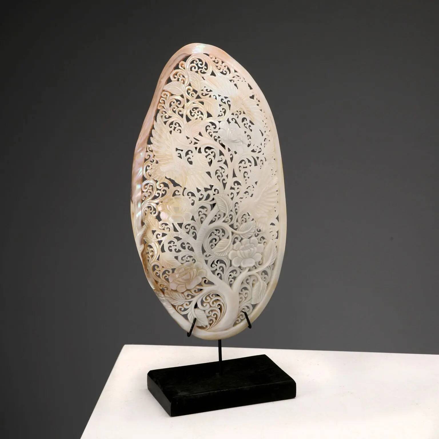 Perforated shell hand-decorated on a wooden base