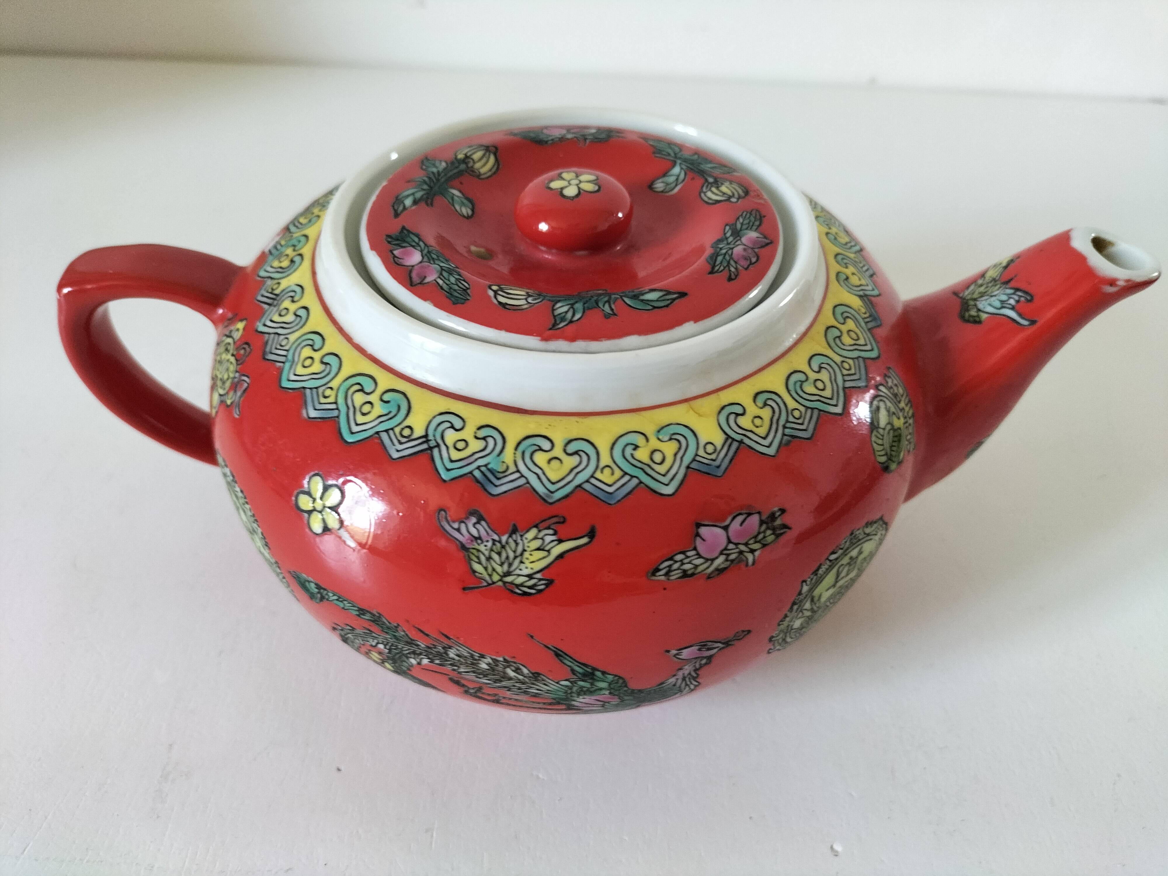 Vintage red Chinese teapot decorated with dragons and symbols.