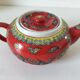 Vintage red Chinese teapot decorated with dragons and symbols.