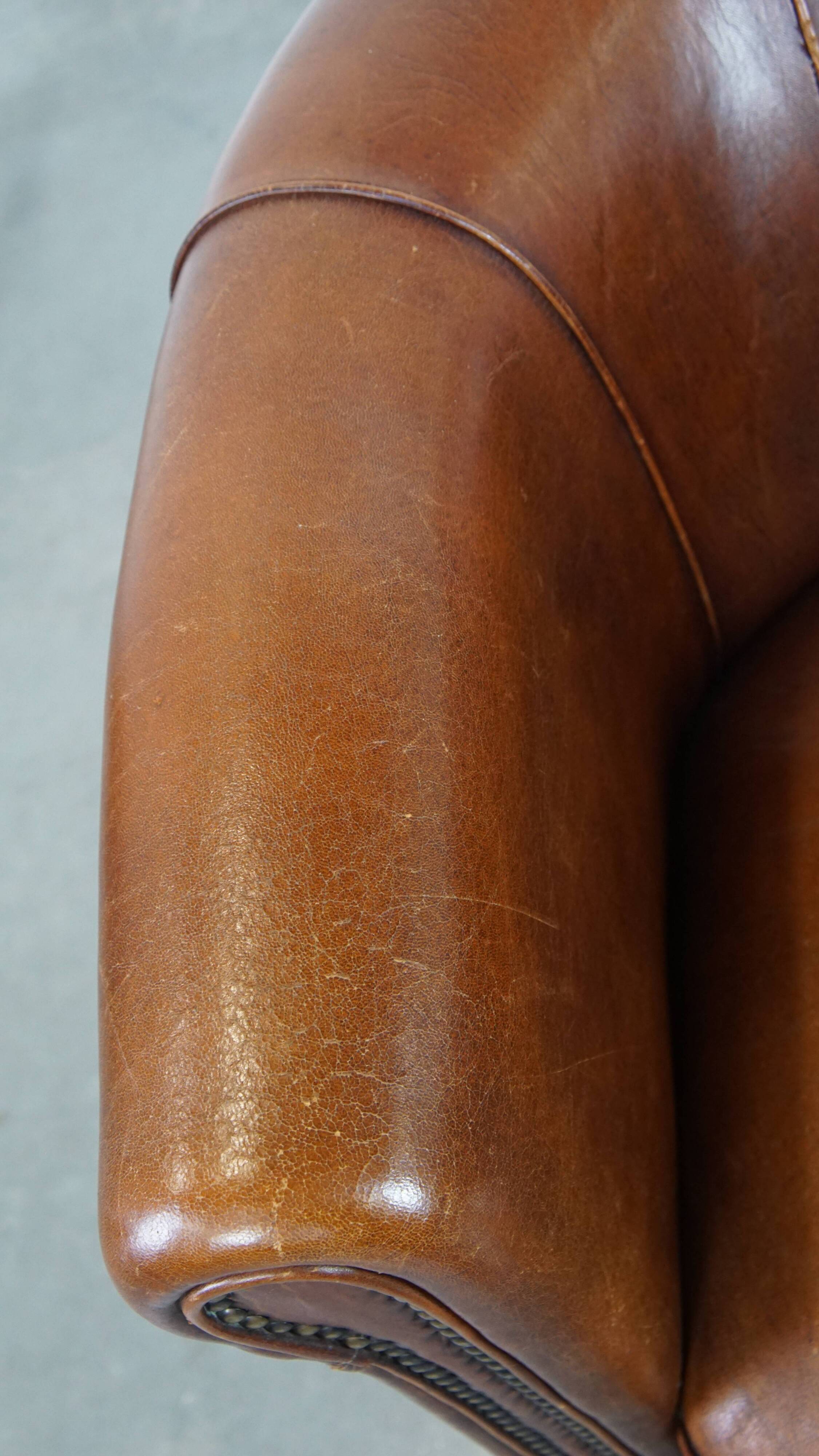 Sheep leather club chair in a cognac color and finished with piping