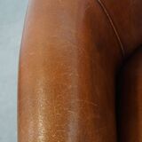 Sheep leather club chair in a cognac color and finished with piping