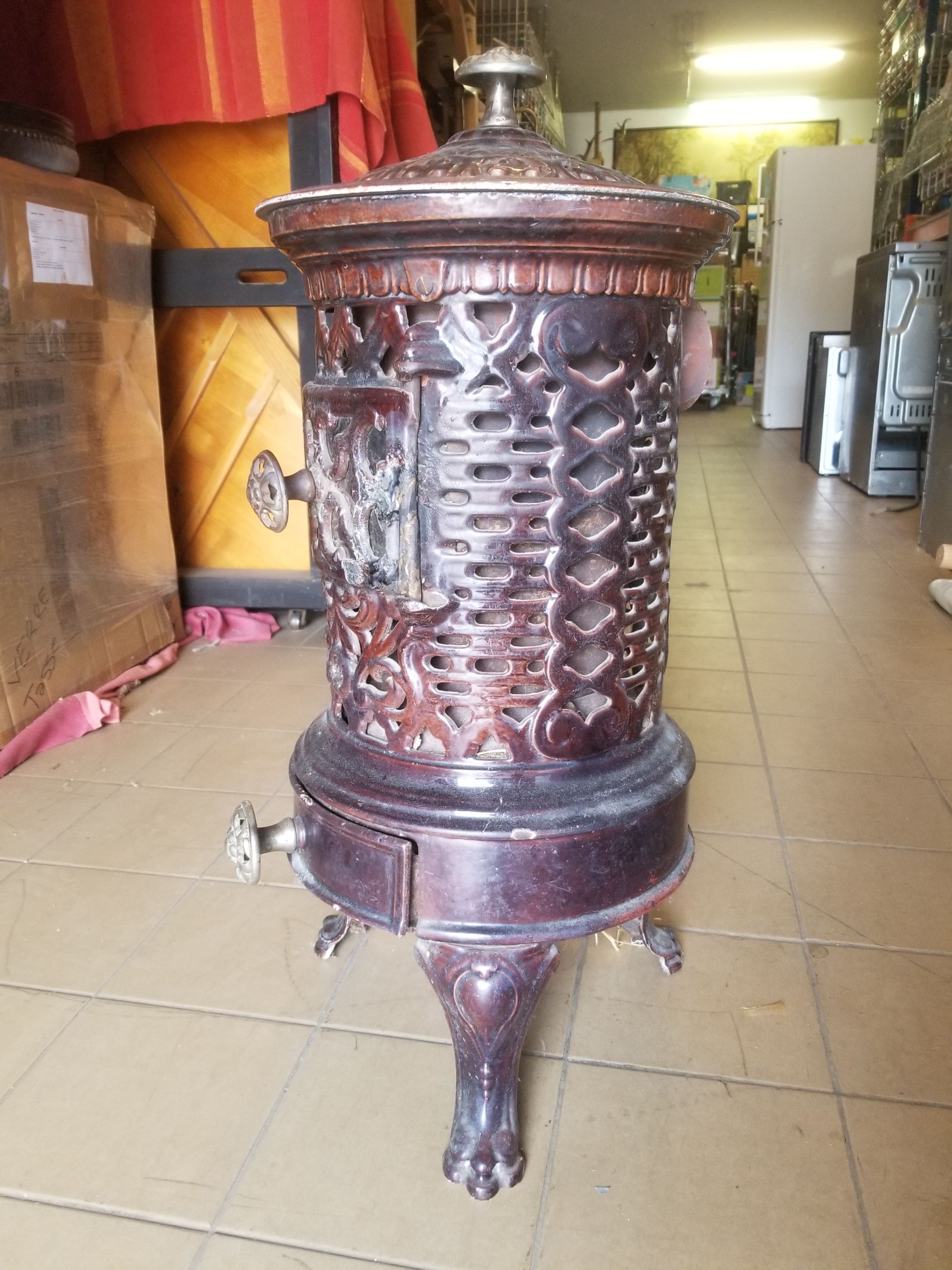 Old compact wood stove in enamelled cast iron with tripod feet with Lion's legs