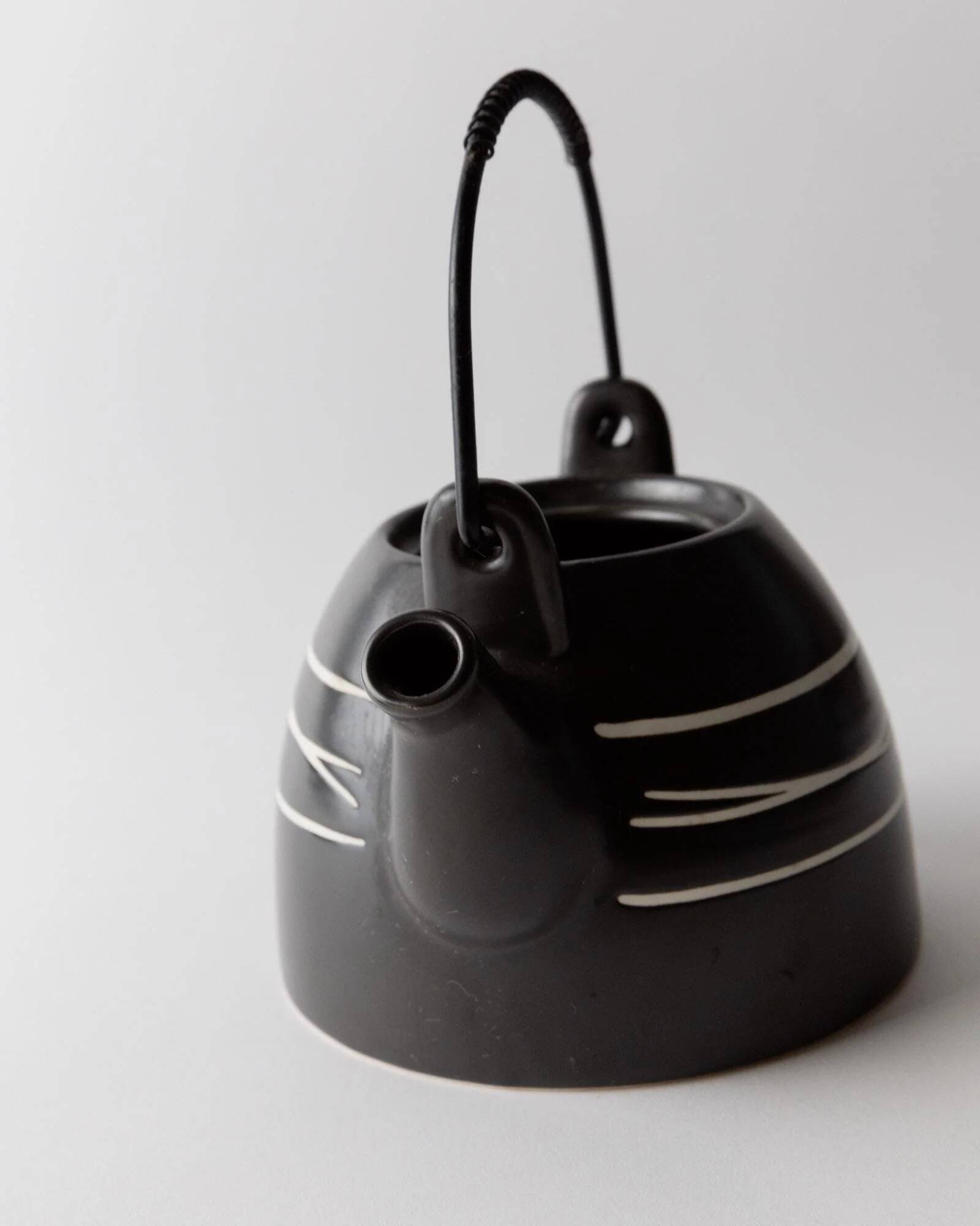 Vintage ceramic teapot from the 1980s, black with white stripes and a metal handle.