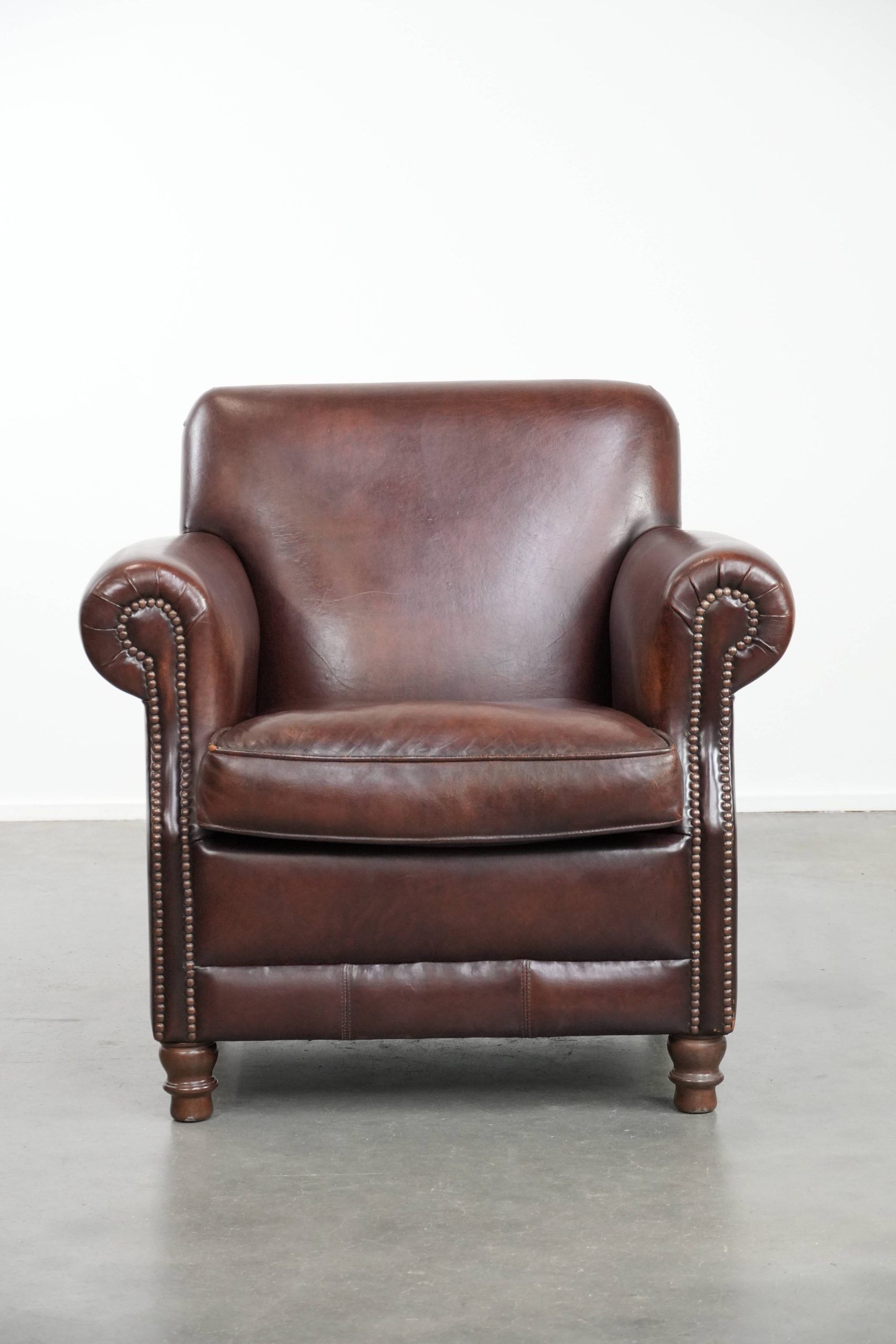 Sheepskin armchair with a classic finish and decorative studs.