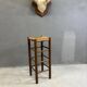 Vintage rustic style bar stool made of solid wood with a straw seat.