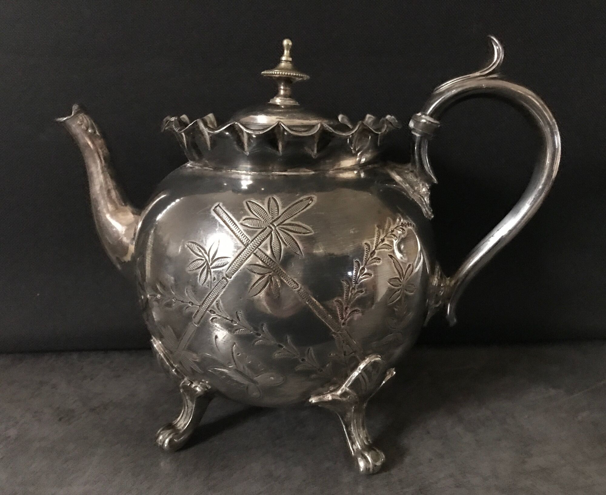 Old teapot pourer in silver metal decorated with foliage and butterflies