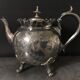 Old teapot pourer in silver metal decorated with foliage and butterflies