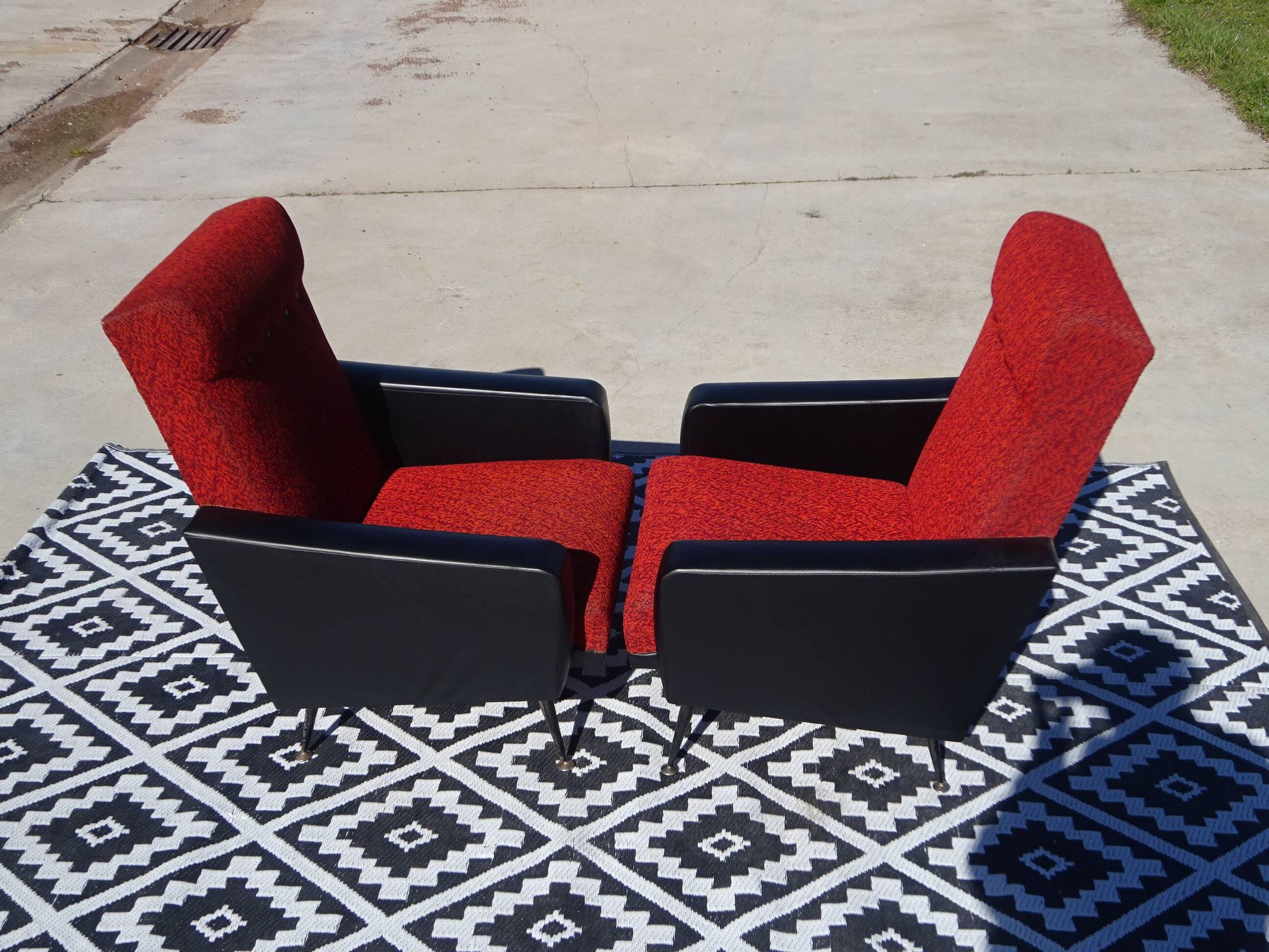 Pair of vintage armchairs in black faux leather and red fabric.